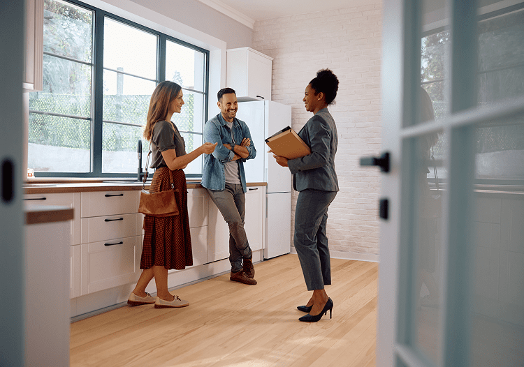 Three people discussing in a modern kitchen with natural light.