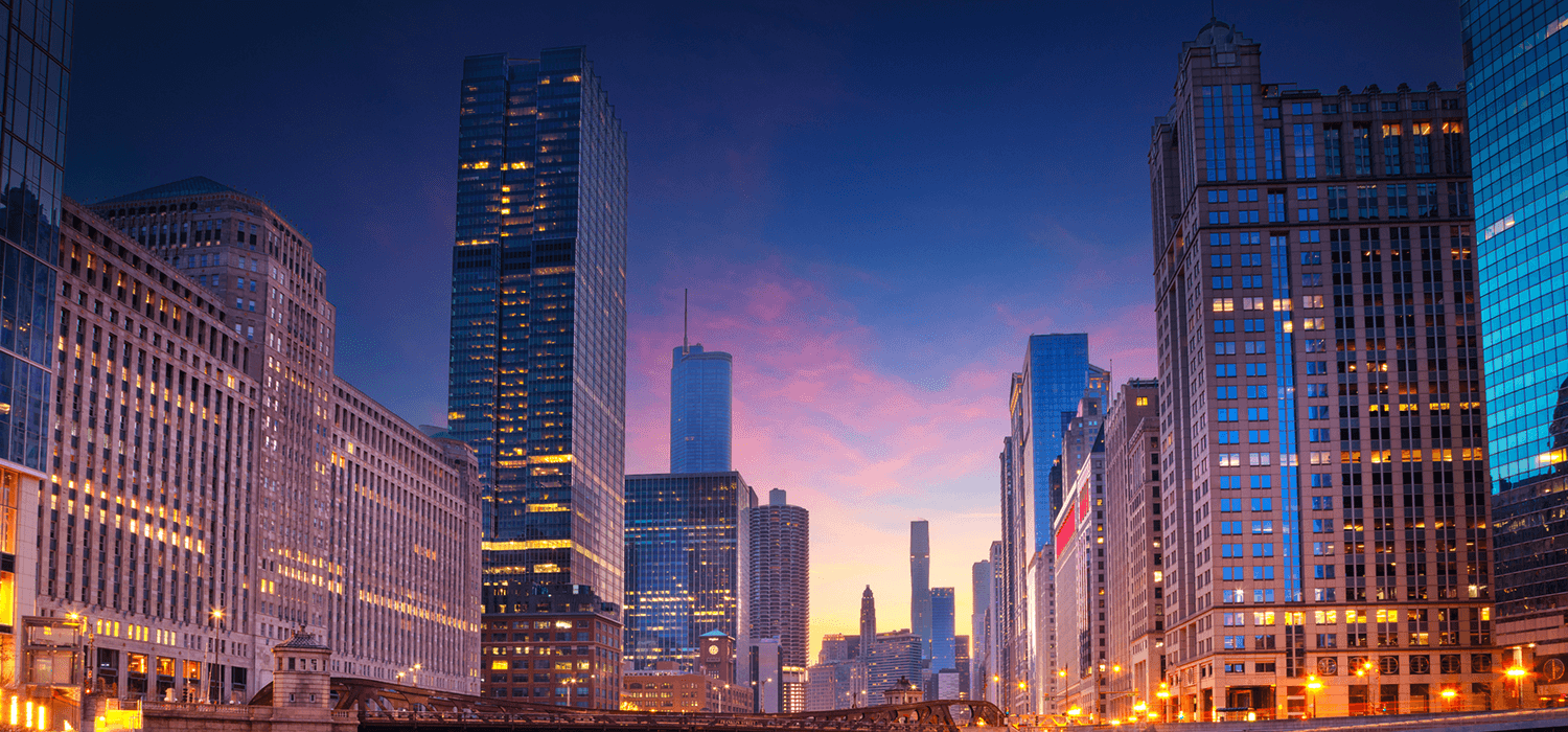 City skyline at dusk with illuminated skyscrapers and vibrant sky.